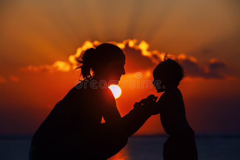 Happy mother and joyful son sunset silhouette