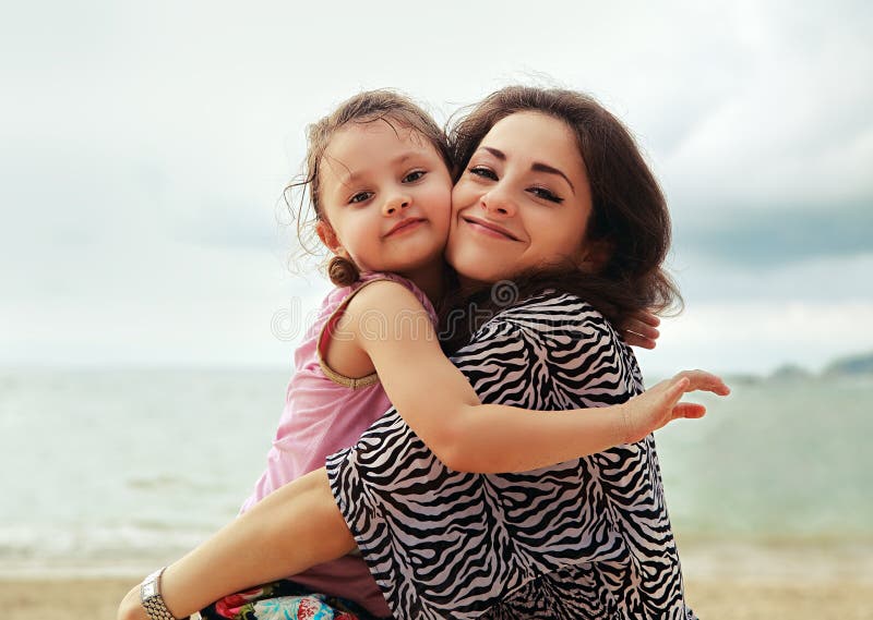 Happy mother and kid girl hugging with natural emotion smiling o
