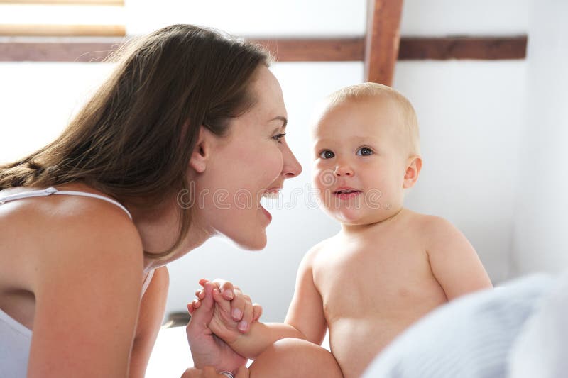 Happy mother playing with baby in bed