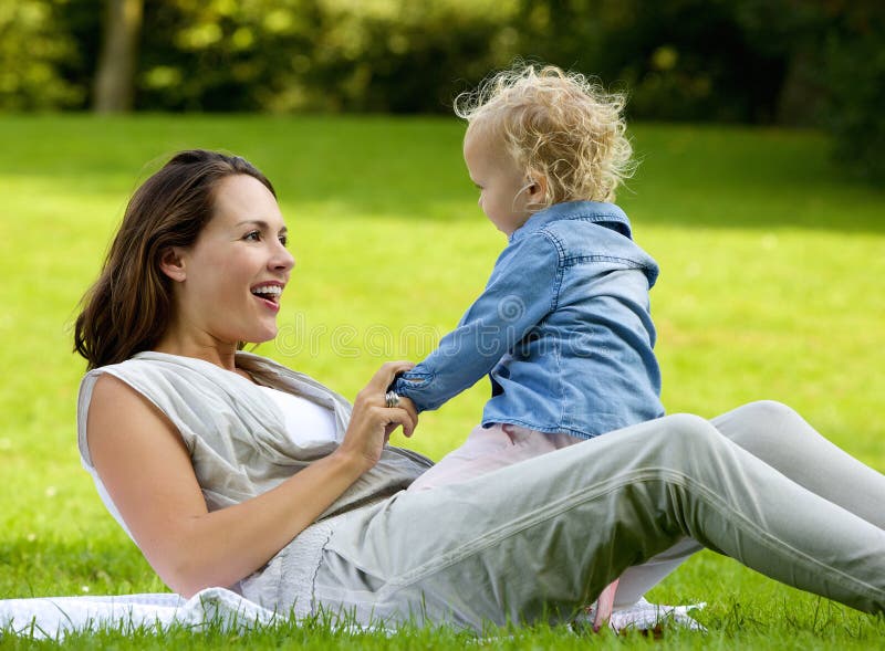 Happy mother playing with baby daughter outdoors