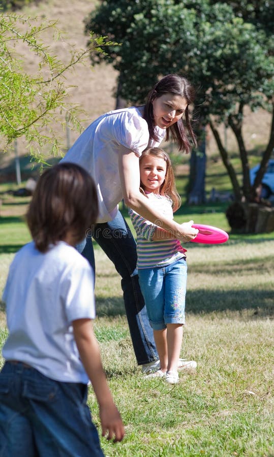 Happy mother playing Frisbee with her children in a park
