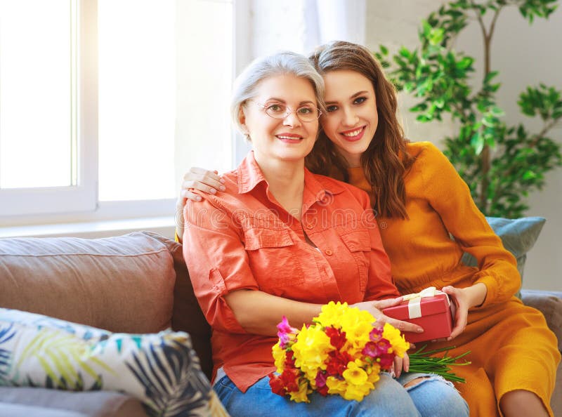 Happy mother`s day! adult daughter gives flowers and congratulates an elderly mother on the holiday