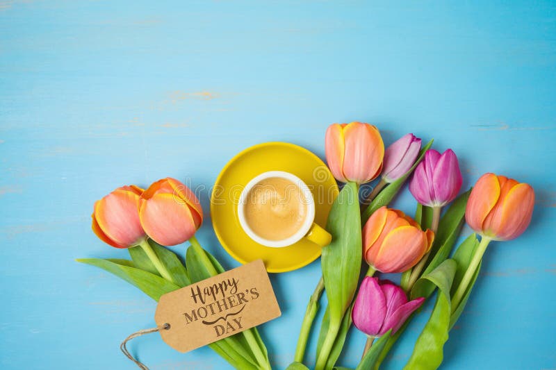 Happy Mother`s day concept with coffee cup and beautuful tulip flowers on woooden background. Top view from above