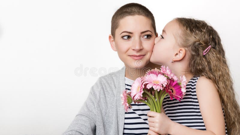 Happy Mother`s Day, Women`s day or Birthday background. Cute little girl giving mom, cancer survivor, bouquet of pink gerbera daisies. Loving mother and daughter. Happy Mother`s Day, Women`s day or Birthday background. Cute little girl giving mom, cancer survivor, bouquet of pink gerbera daisies. Loving mother and daughter.