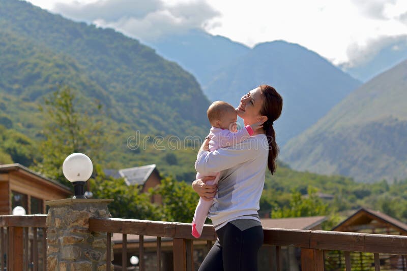 Happy mother with a small child standing on the terrace of a country house surrounded by mountains royalty free stock photos Happy mother with a small child standing on the terrace of a country house surrounded by mountains royalty free stock photos
