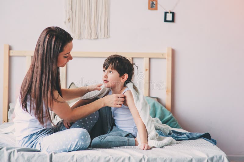 Mother and child son enjoying weekend morning in bed, casual lifestyle. 