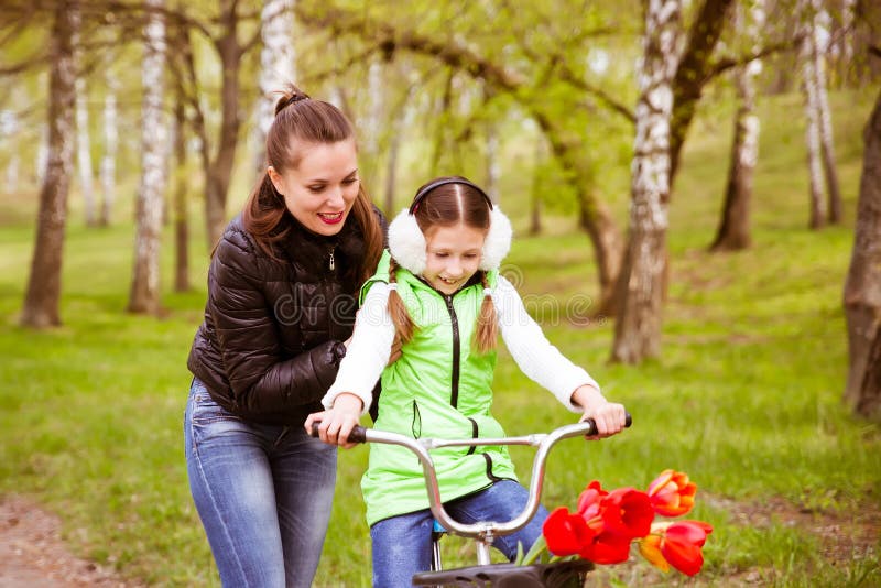 Happy mother teaches his daughter to ride a bike. Mother holds daughter from falling royalty free stock image Happy mother teaches his daughter to ride a bike. Mother holds daughter from falling royalty free stock image
