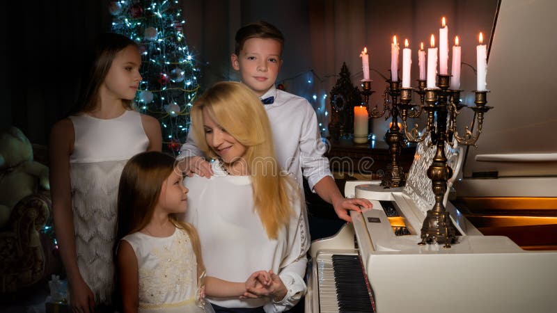 Happy mother with children near a white grand piano stock photo