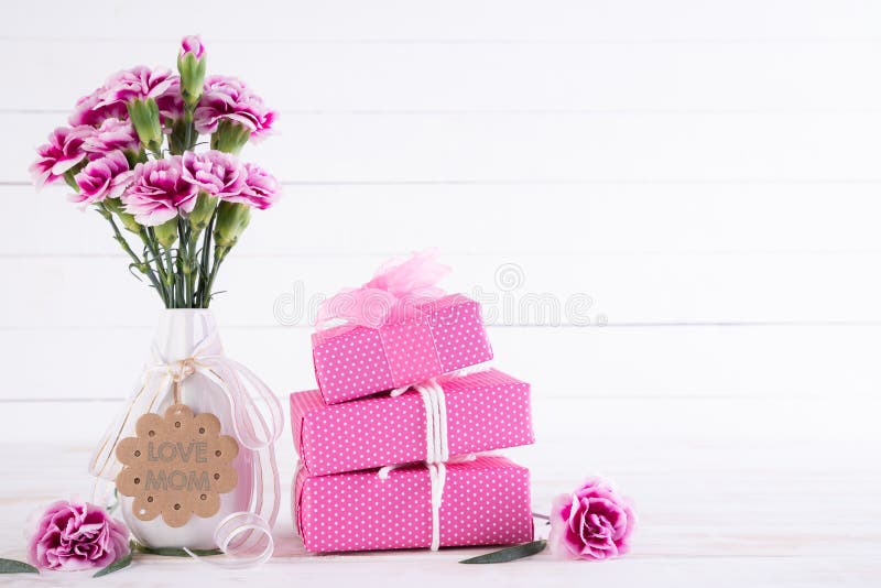 Happy mothers day concept. Gift box with pink carnation flower on white wooden table background