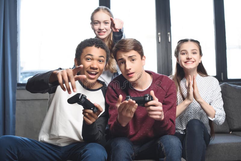Happy multicultural teenagers playing video games with joysticks at home stock image Happy multicultural teenagers playing video games with joysticks at home stock image