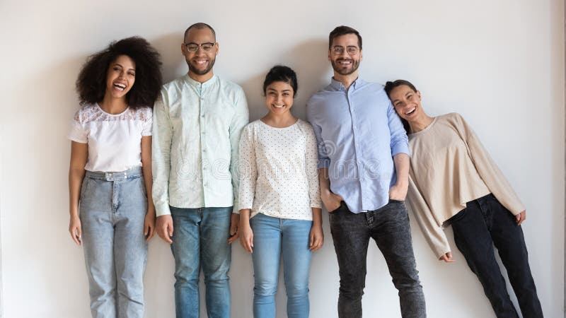 Happy multiethnic young people stand in row look at camera posing for group picture together, funny international millennial friends laugh having fun show unity and support, friendship concept. Happy multiethnic young people stand in row look at camera posing for group picture together, funny international millennial friends laugh having fun show unity and support, friendship concept