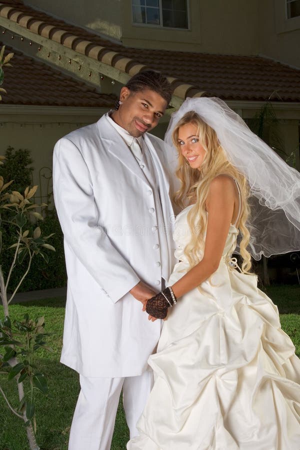 Interracial couple outdoors. Smiling laughing newlywed young Caucasian woman and mid aged ethnic black man of African American and Italian ethnicity. Interracial couple outdoors. Smiling laughing newlywed young Caucasian woman and mid aged ethnic black man of African American and Italian ethnicity