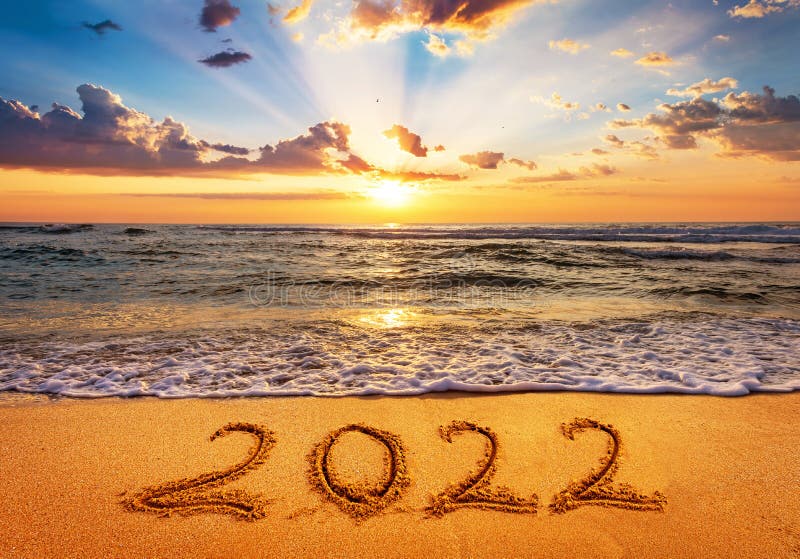 Happy New Year 2022 is coming concept. Number 2022 written on seashore sand at sunrise stock photography