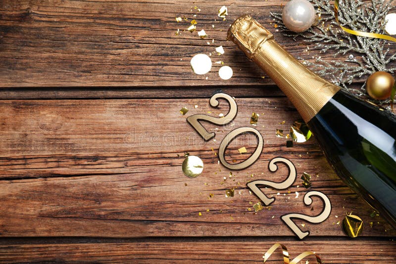 Happy New Year 2022! Flat lay composition with bottle of sparkling wine on wooden table, space for text. Happy New Year 2022! Flat lay composition with bottle of royalty free stock photo