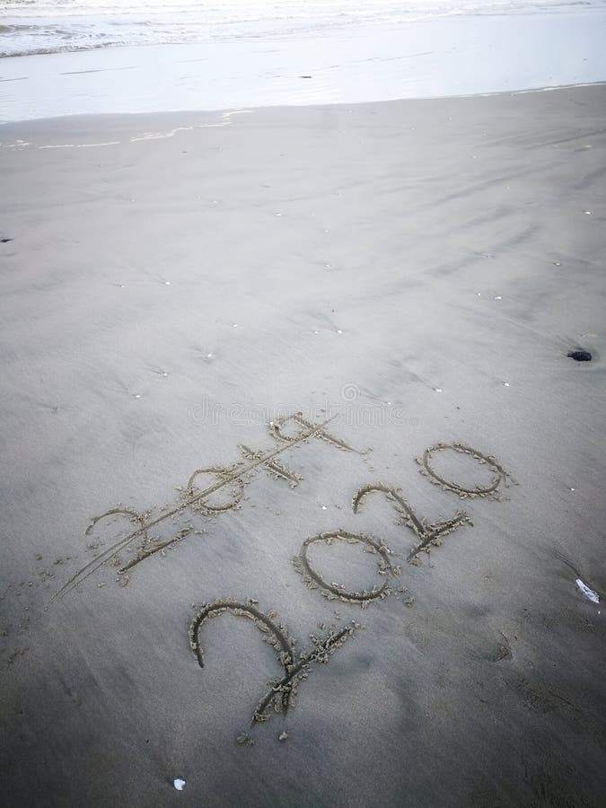 Happy new year 2020, lettering on the beach with wave and clear blue sea. Numbers 2020 year on the sea shore. stock photos
