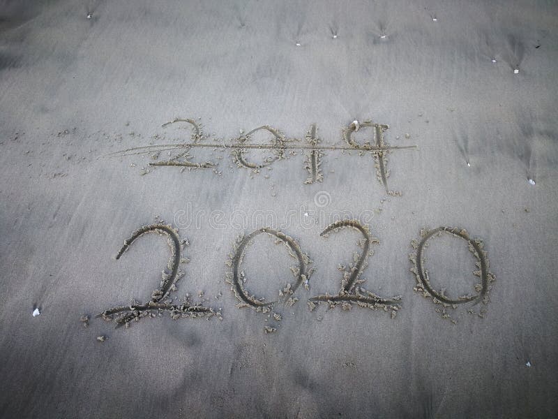 Happy new year 2020, lettering on the beach with wave and clear blue sea. Numbers 2020 year on the sea shore. royalty free stock image