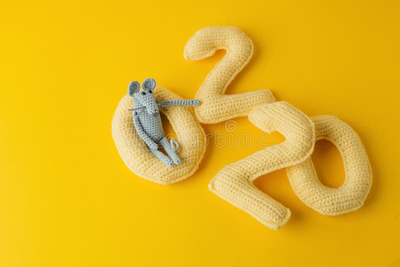 Happy New Year 2020. Number 2020 knitted from yarn and gray toy mouse symbol of year on bright yellow background, cheese color. Fl. At lay, top view, copy space royalty free stock images