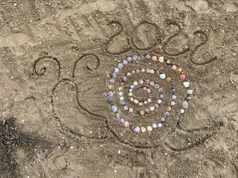 Happy new year 2022, snail with shells in the sand. Happy new year 2022, a snail made with shells in the sand on the beach royalty free stock image