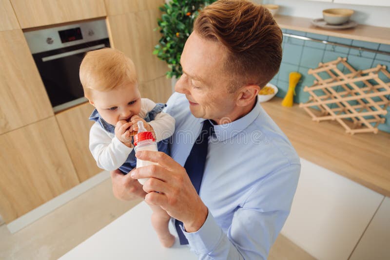 Happy nice man giving a bottle with milk to his baby daughter royalty free stock images Happy nice man giving a bottle with milk to his baby daughter royalty free stock images