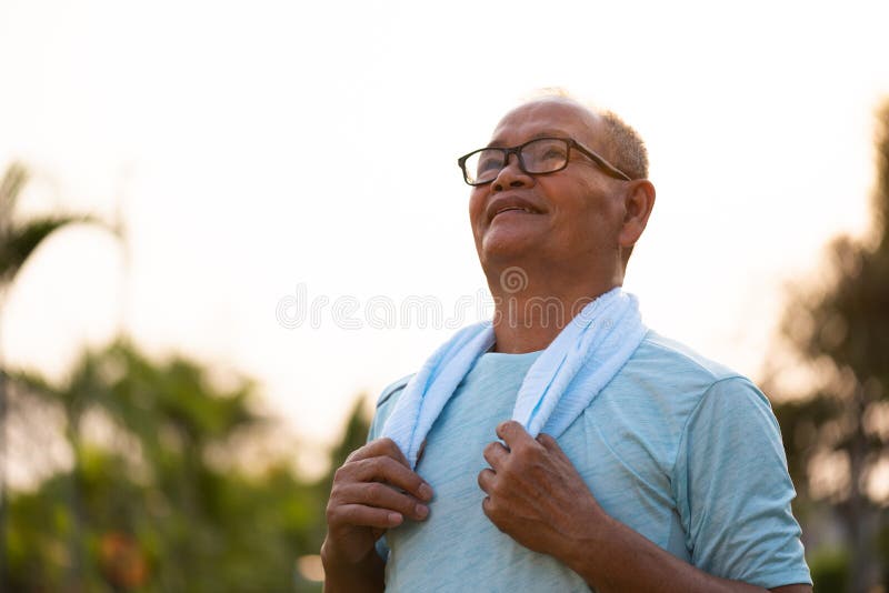 A happy old asian man is relaxing and breathing fresh air at park with sunlight. Healthcare and senior sports concept