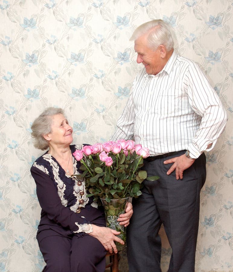 Happy old couple and big bouquet of pink roses