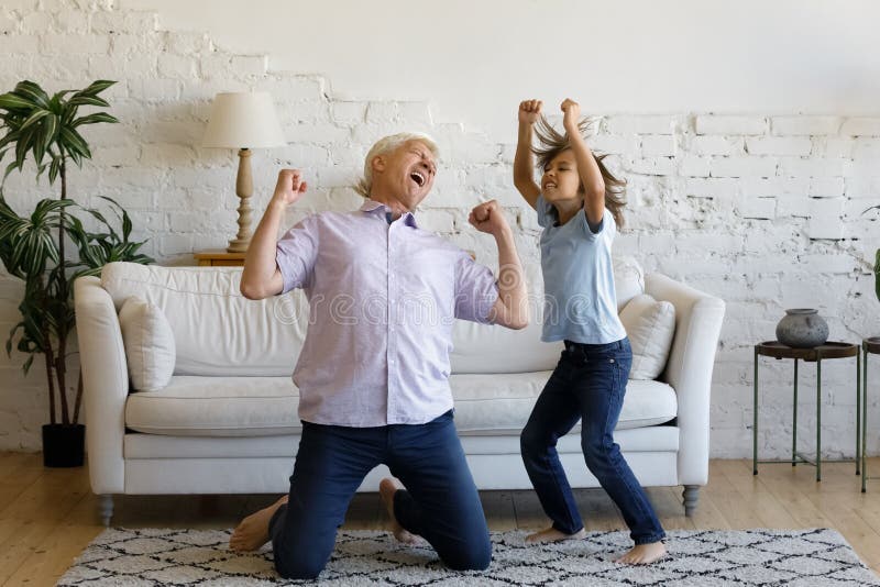Happy Old Man Dancing With Preteen Grandson At Home Stock Image