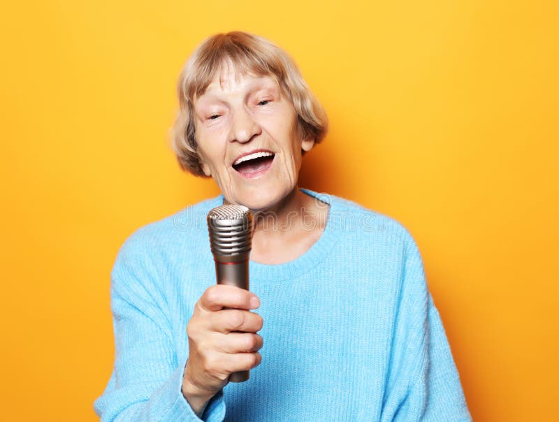 Happy Old Senior Woman Singing With Microphone Having Fun Expressing