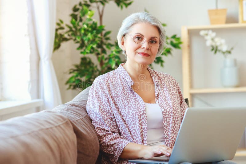 Happy old woman senior working at computer laptop at home stock photos