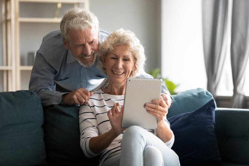 Happy older couple using computer tablet together at home