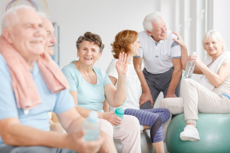 Happy older people sitting together in a gym after training