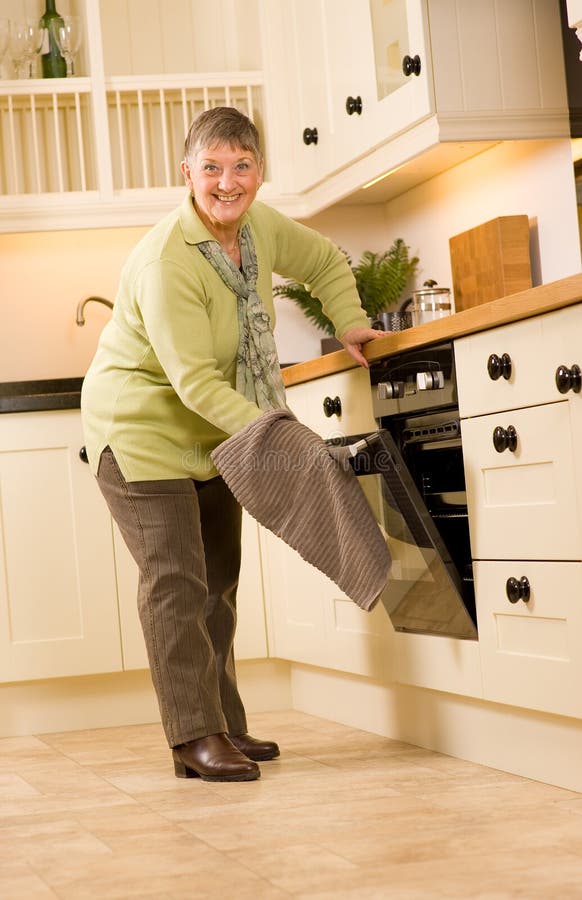 Happy older woman is designer kitchen