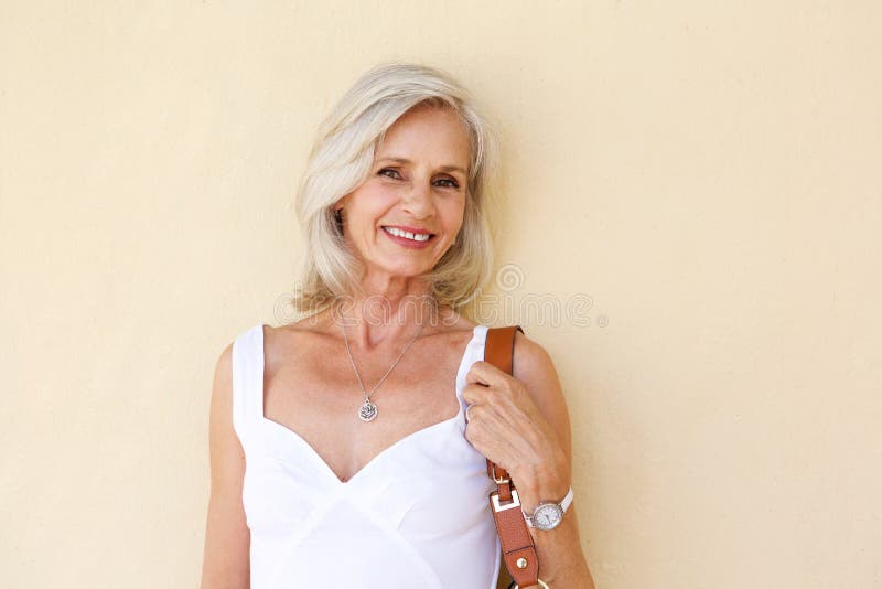 Happy older woman standing in spring dress with purse