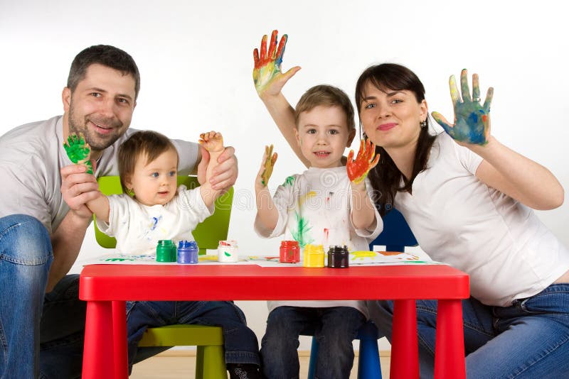 Happy parents with their children enjoy painting with assorted colours on hands. Happy parents with their children enjoy painting with assorted colours on hands