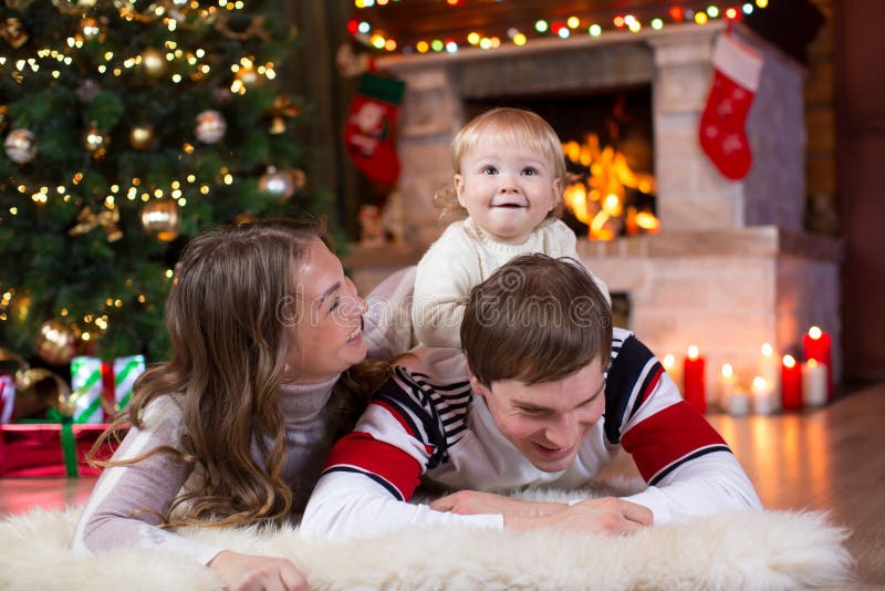 Happy parents and child play near Christmas tree at home. Father, mother and son celebrating New Year together royalty free stock images Happy parents and child play near Christmas tree at home. Father, mother and son celebrating New Year together royalty free stock images