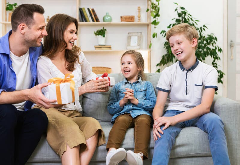 Happy Parents Giving Gifts To Kids Celebrating Holiday Sitting Indoors ...