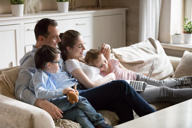 Parents cuddle with children watching kid video at laptop stock image Parents cuddle with children watching kid video at laptop stock image