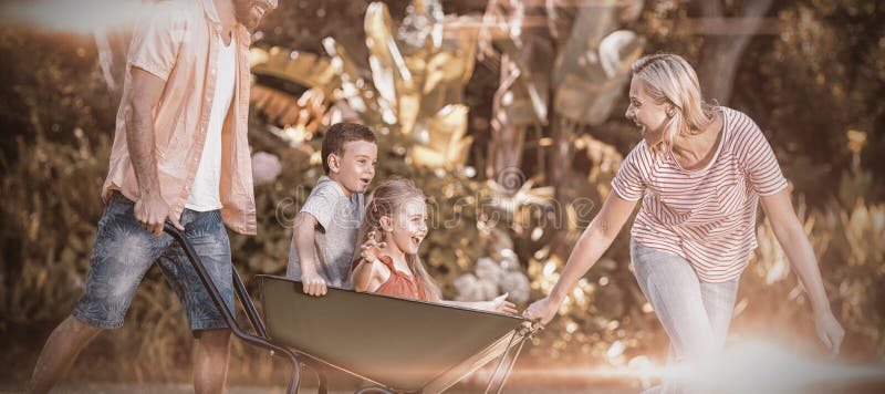 Parents pushing children sitting in wheelbarrow at yard stock images Parents pushing children sitting in wheelbarrow at yard stock images
