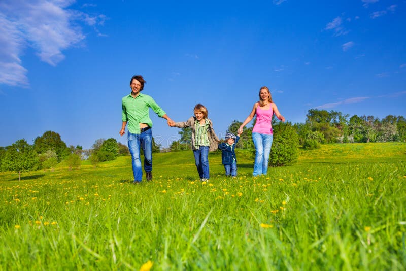 Happy parents holding hands with boys and walking in the park. Happy parents holding hands with boys and walking in the park