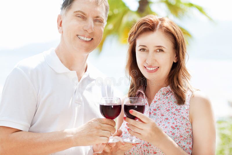Happy people concept in summer vacation : beautiful middle-aged couple drink wine on the sea background stock photos Happy people concept in summer vacation : beautiful middle-aged couple drink wine on the sea background stock photos