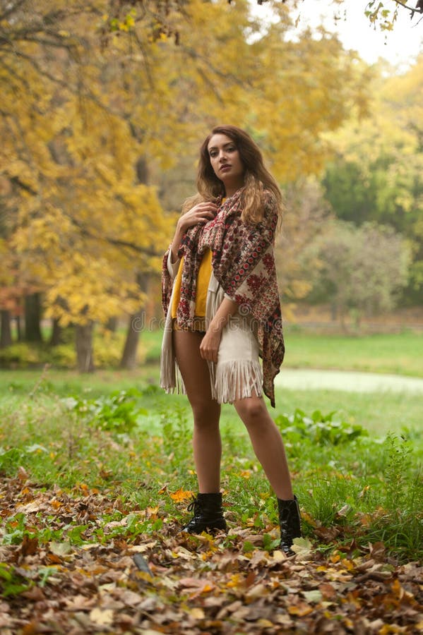 Happy Portrait d'une belle jeune femme du Caucase avec foulard, jambes longues et pull-over jaune dans le parc d'automne images stock Happy Portrait d'une belle jeune femme du Caucase avec foulard, jambes longues et pull-over jaune dans le parc d'automne images stock