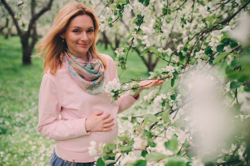 Happy pregnant blonde beautiful woman walking outdoor in spring park or garden