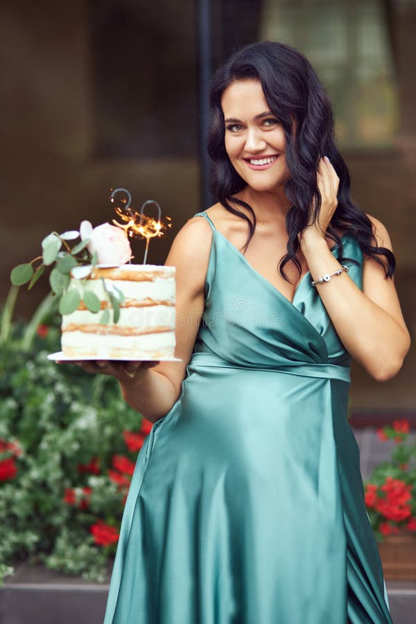 A Happy Pregnant Brunette in a Green Dress is Holding a Birthday Cake ...