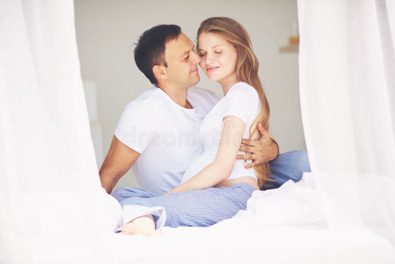 Happy pregnant couple embracing in bedroom in the morning stock images Happy pregnant couple embracing in bedroom in the morning stock images
