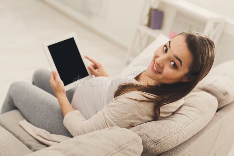 Happy pregnant woman using digital tablet at home