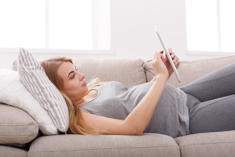 Happy pregnant woman using digital tablet.