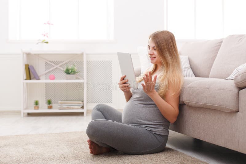 Happy pregnant woman using digital tablet.