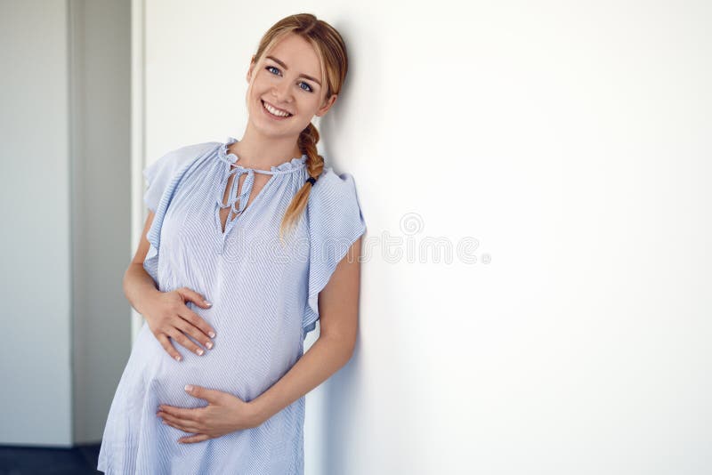 Happy pregnant young woman cradling her belly