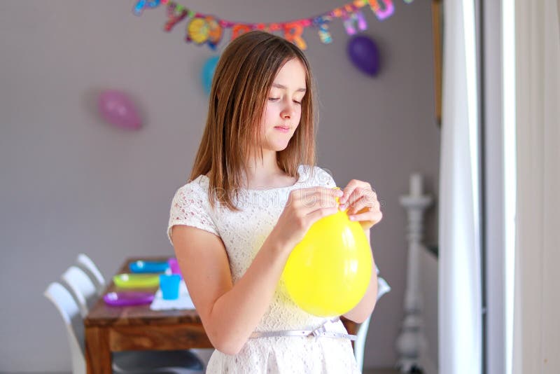 Happy preteen girl blowing yellow balloon decorating house preparing to kids birthday party