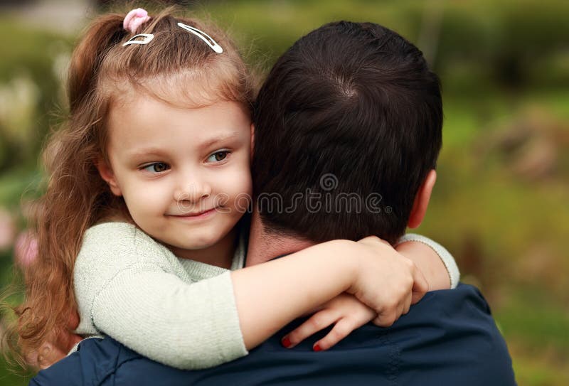 Happy pretty smiling kid girl hugging her father with love outdo