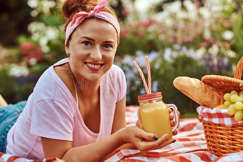 Happy Redhead Middle Age Female In Casual Clothes With A Headband Enjoying During Picnic